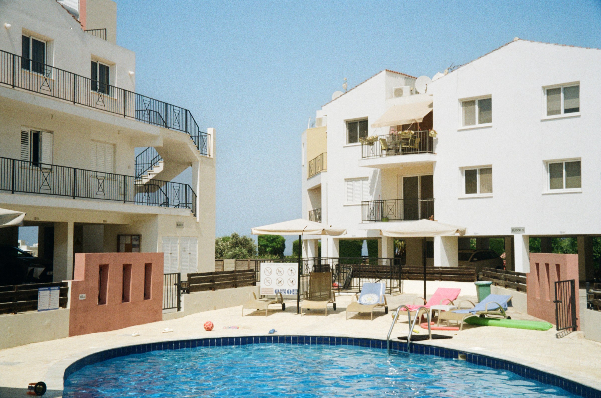 A pool surrounded by loungers with apartment buildings behind