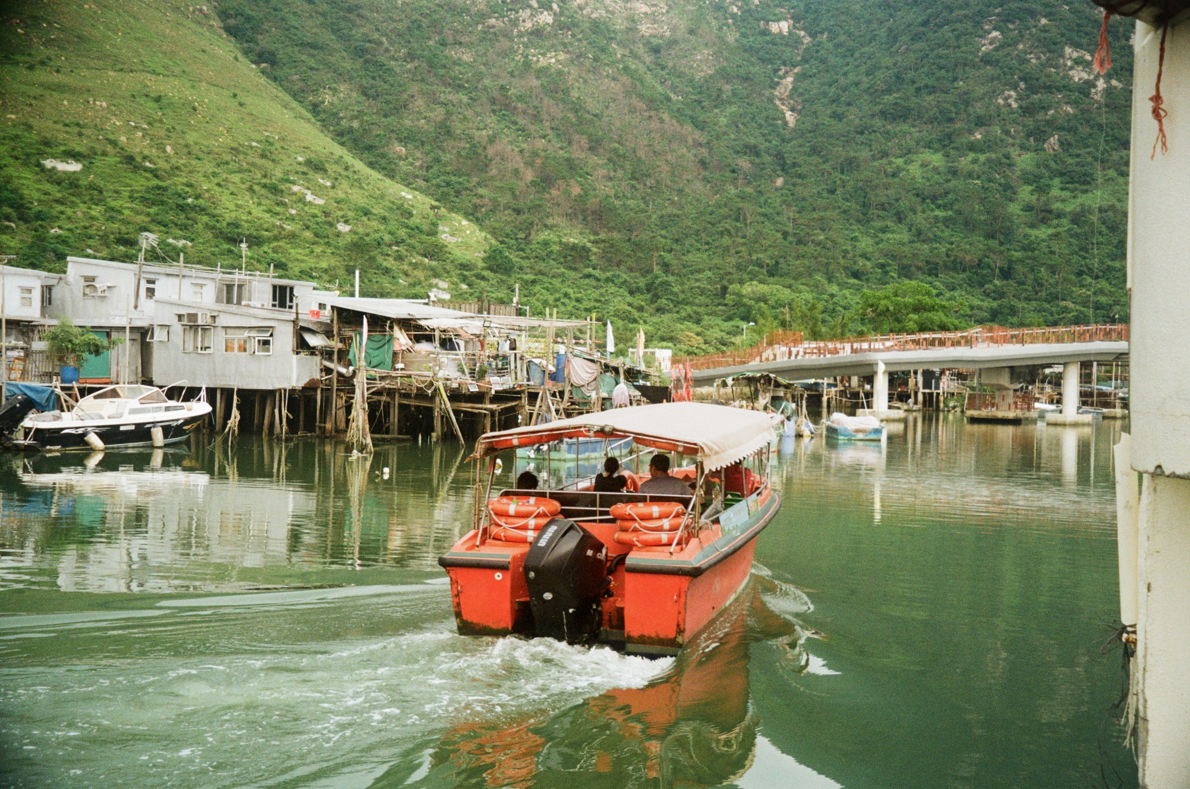 A red speedboat pulling away through Tai O canal